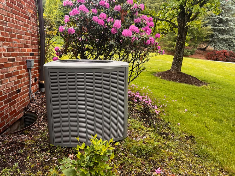 Air conditioning unit sitting outside in grass.