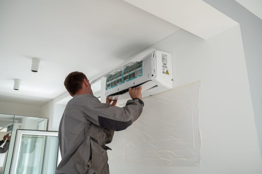 Technician repairing mini-split on wall.